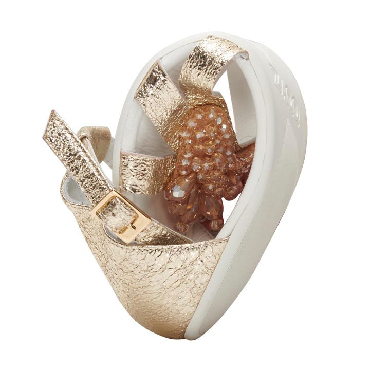 The QISELLE gold sandal from ZAQQ is a striking design with sculptural gold and white details and glittering crystal-like embellishments on the sole. It features textured straps in signature QISELLE gold and a smooth white base crafted from premium Nappa leather, offering both artistry and luxury.