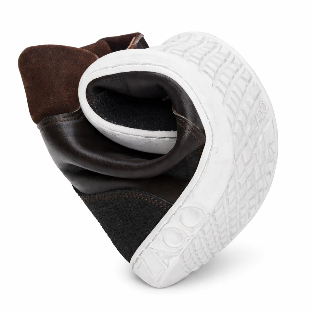 The MINSQ Dark Brown Sneaker from ZAQQ Made from black leather with a mid-cut cut, it bends in the middle to show off its flexibility. Its white rubber sole features a textured pattern and clearly shows the brand name ZAQQ. This style of barefoot shoe also features a pull tab on the back.