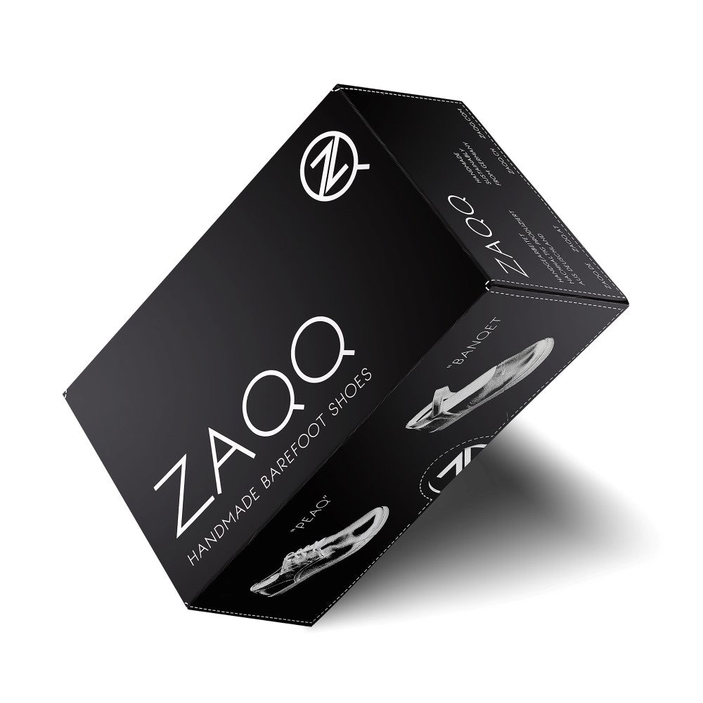 A black one ZAQQ-Shoe box is positioned to show multiple sides, highlighting the brand logo and the words “Handmade Barefoot Shoes.” The elegant design alludes to the collection, which includes the eye-catching SPIQE Red Black sneaker, and features images of the famous barefoot shoe on the sides.