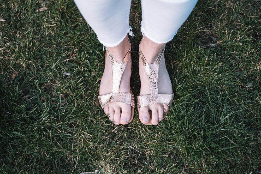 With these CLIQ gold sandals from ZAQQ is a pair of shiny metallic shoes with a T-strap design and buckle closure and a flexible sole for comfort.