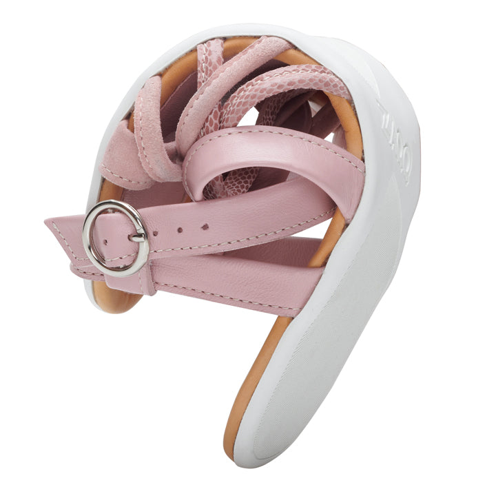 Close-up of a QORY pink ballet shoe from ZAQQ, which is decorated in delicate pink and is reminiscent of a strappy sandal. It features mesh details and a buckled strap, and its flexible sole is curved to highlight its flexibility, all against a white background.