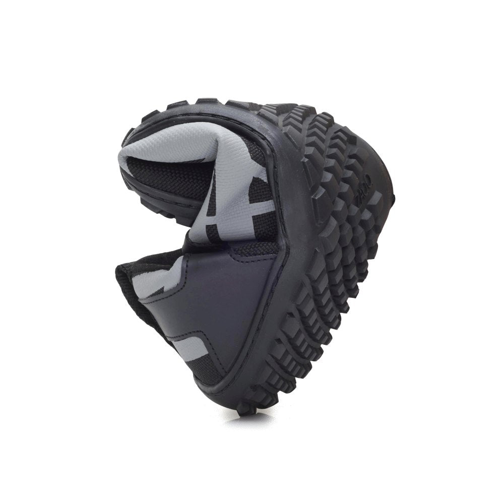 A close-up of the XIQOT Black from ZAQQ, a black and gray running shoe that is curved in the middle illustrates his flexibility. It features a sturdy, deep tread sole made from flexible rubber sole, making it ideal for outdoor adventures. The upper is made of vegan mesh fabric and offers both durability and sustainability.