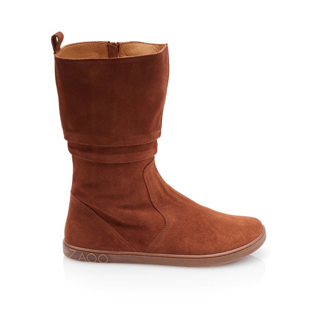 A single brown goatskin suede boot is presented against a white background. The ZAQQ QOM Cognac barefoot shoe has a mid-cut design, a discreet zipper on the outside and a top loop for easy carrying.