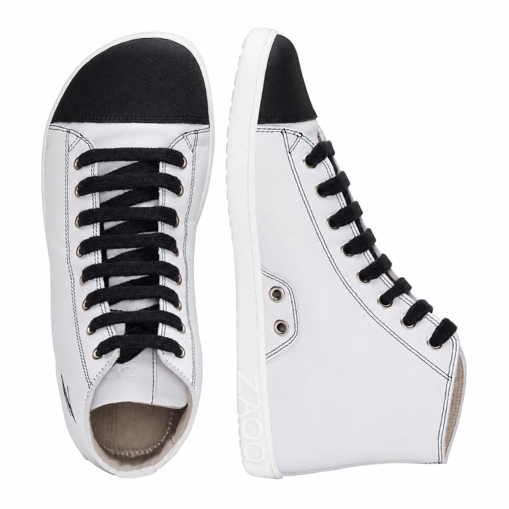 We present the CHUQQS White by ZAQQ: a pair of elegant white high-top sneakers with black laces and toe caps. The left shoe is seen from top to bottom, while the right shoe stands upright showing its side profile. These sneakers are expertly crafted from nappa leather and have white soles with the brand name ZOOZ.