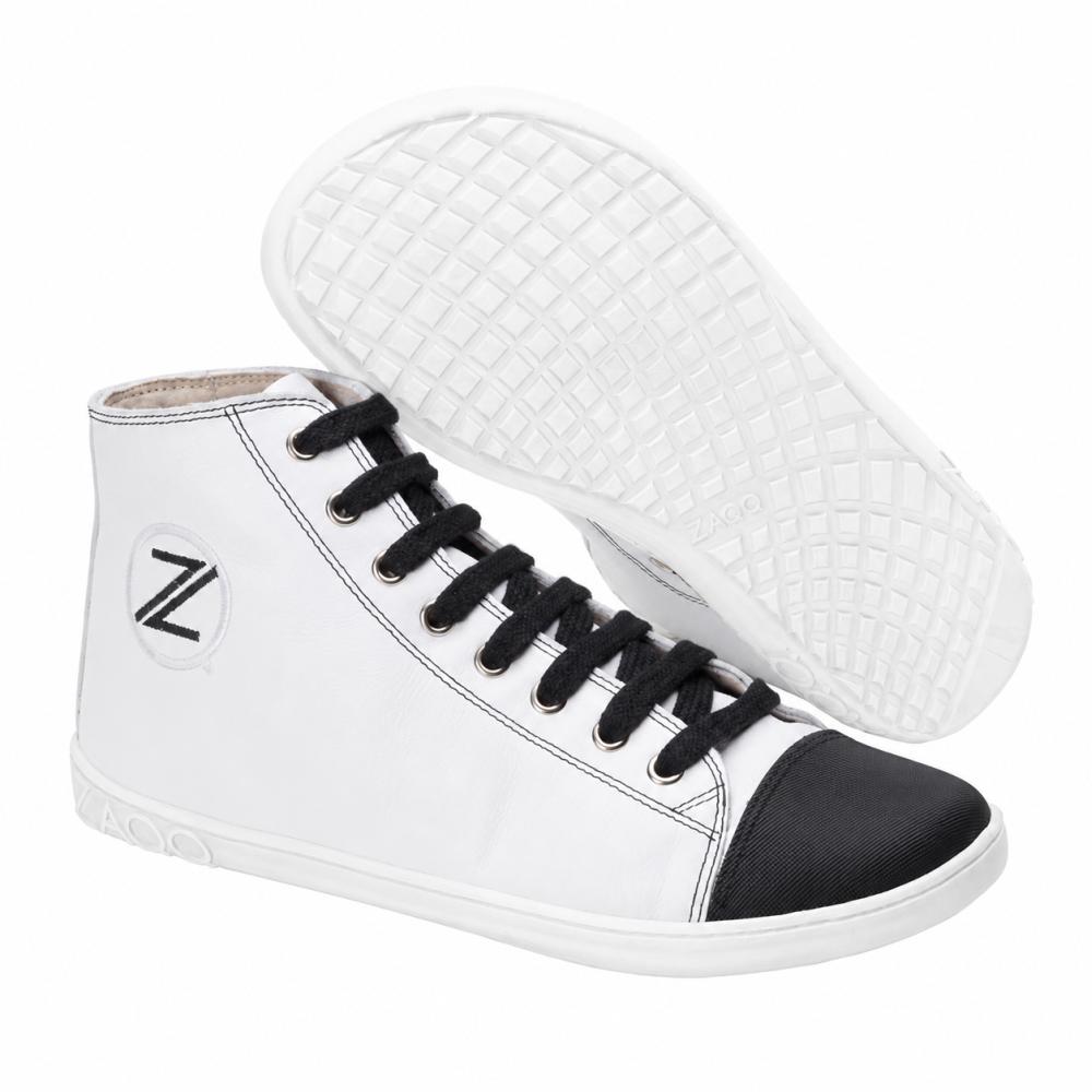 We present the CHUQQS White by ZAQQ, a stylish pair of high-top sneakers with white upper material, black toe cap, and black laces. These sneakers feature a textured sole with a grid pattern and prominently display the brand's Z-logo on the side. The white sneaker seamlessly combines classic style with modern comfort.