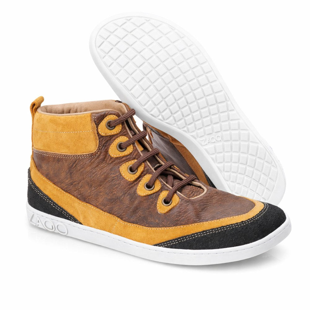 Die FRANQY Brown High-Top-Sneaker von ZAQQ bieten außergewöhnlichen Tragekomfort mit ihrer Kombination aus braunem Leder und Wildleder, ergänzt durch Metallösen und braune Schnürsenkel. Mit weißen Gummisohlen steht ein Schuh aufrecht, während der andere geneigt ist, um seine gemusterte Sohle zur Geltung zu bringen.
