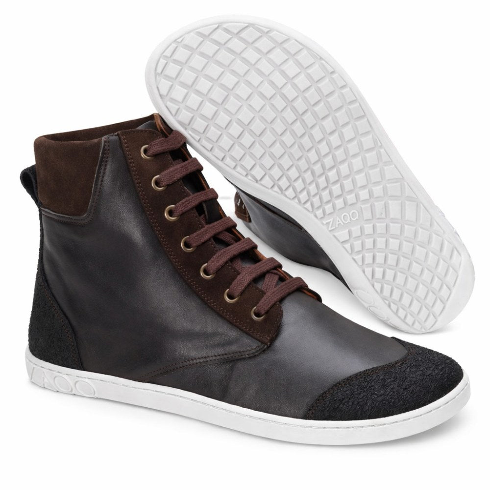 A pair of dark brown MINSQ mid-cut sneakers from ZAQQ has a white sole. One shoe stands upright, showing off its leather material and brown laces, while the other stands at an angle, showing off the textured sole. The brand's logo is visible on the sole and underlines the stylish design.