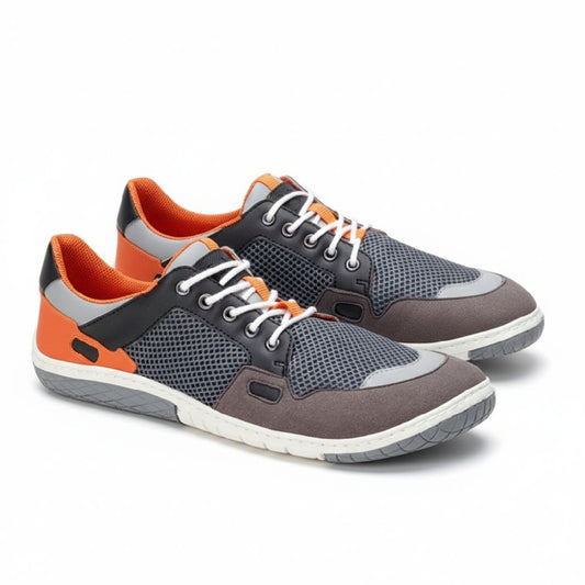 Wir präsentieren den NUQA Grey von ZAQQ, ein Paar schicke Sneaker aus veganem Mesh-Gewebe, das sich durch eine Mischung aus grauem Mesh und orangefarbenen Akzenten auszeichnet. Sie kommen mit weißen Schnürsenkeln, einem schwarzen Detail in Knöchelnähe und sind mit einer langlebigen und dennoch flexiblen ZAQQ MINIMAL-Sohle ausgestattet.