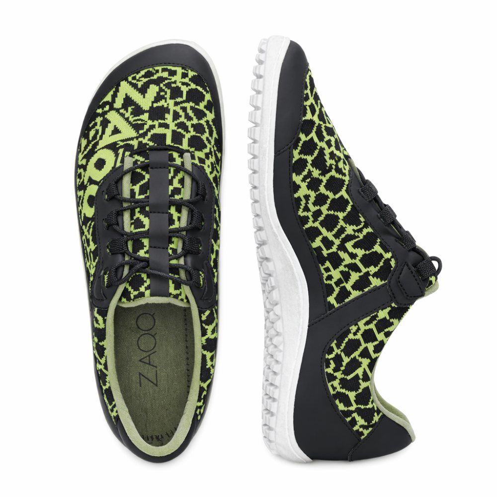 The QASEY Green from ZAQQ are a pair of shoes with a black and green pixel pattern made from vegan materials. They have black laces, a black sole with white accents and the word ZAO is visible on the inside. One shoe is seen from above while the other shows its side profile.