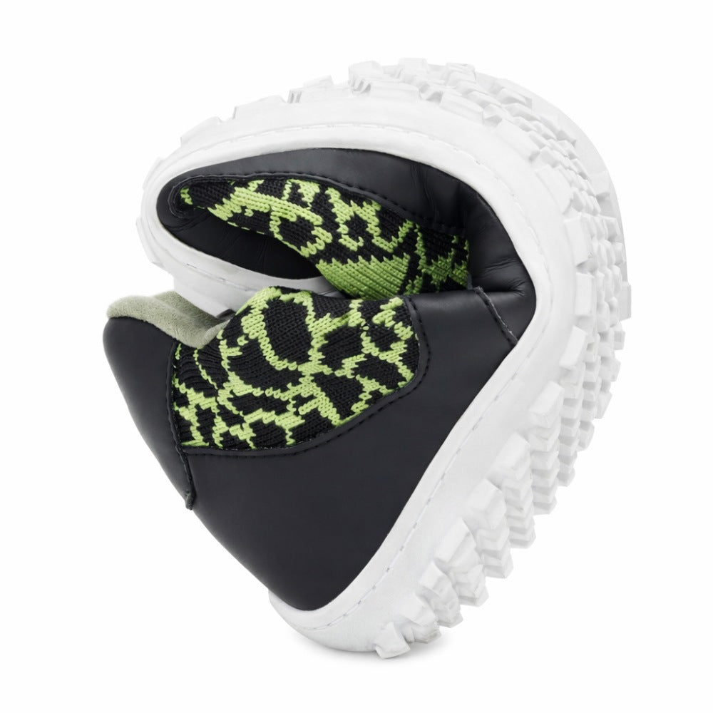 A pair of QASEY Green shoes from ZAQQ with a black and green pattern, made from vegan materials with thick white soles, are folded into a heart shape to demonstrate their flexibility.