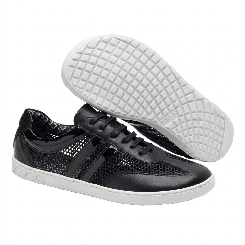 Das Bild zeigt ein Paar schwarze QIMBERLY-Sneaker mit einem eleganten schwarzen Mesh-Design und kontrastierenden weißen Sohlen. Ein Schuh steht aufrecht, um seinen Stil zu betonen, während der andere angewinkelt ist, um das markante Gittermuster auf der Sohle zu zeigen. Das ZAQQ-Logo ist deutlich zu sehen und unterstreicht den atmungsaktiven Komfort, der sie perfekt für den ganztägigen Gebrauch macht.