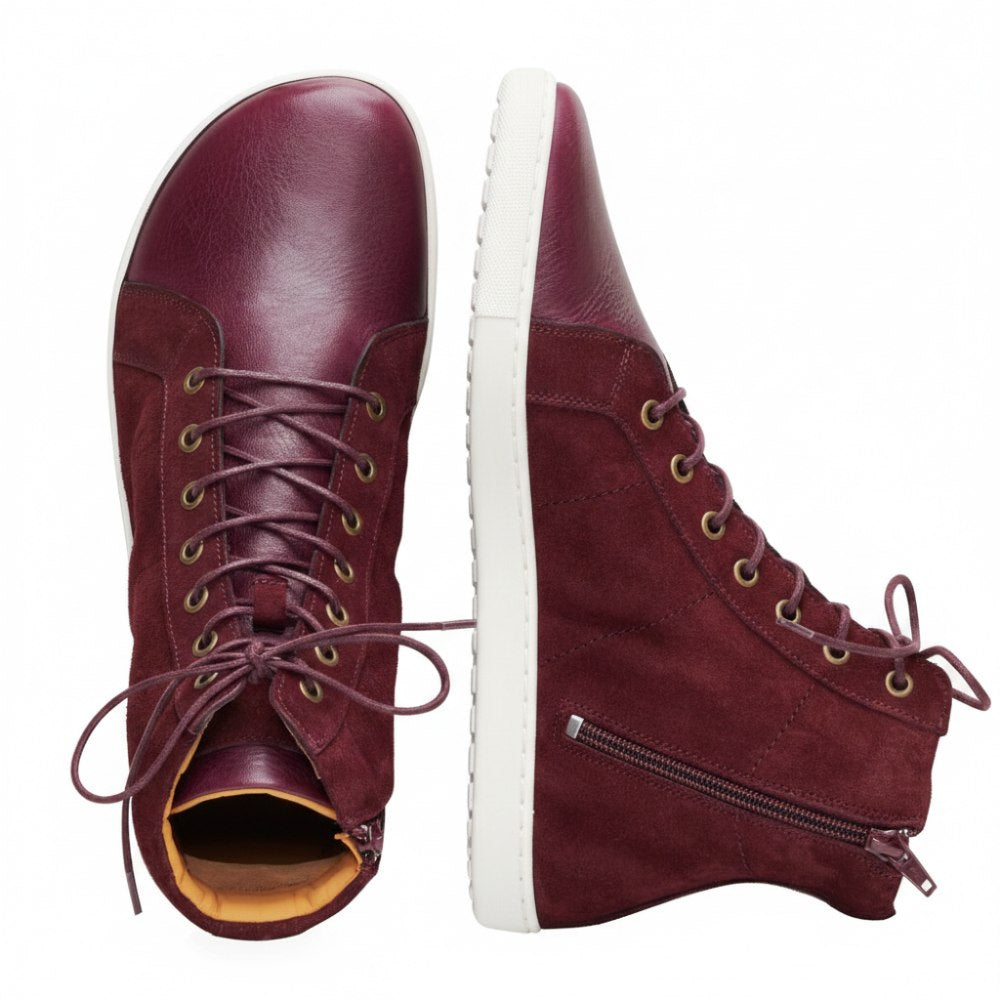 The QORE High Mazarine shoes are presented in chestnut brown, one stands upright, the other is flat. These mid-height sneakers from ZAQQ are made of suede and smooth leather, have side zippers and a textured sole that proudly displays the brand logo.