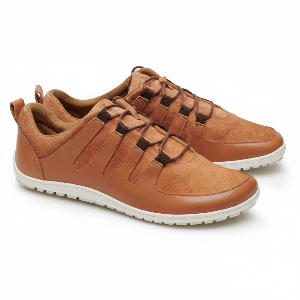 The SHOQQ cognac from ZAQQ is a brown casual shoe made of leather with laces and a white rubber sole that offers exceptional comfort. These shoes feature a smooth surface with stitching and tabs on the back arranged side by side on a white background.