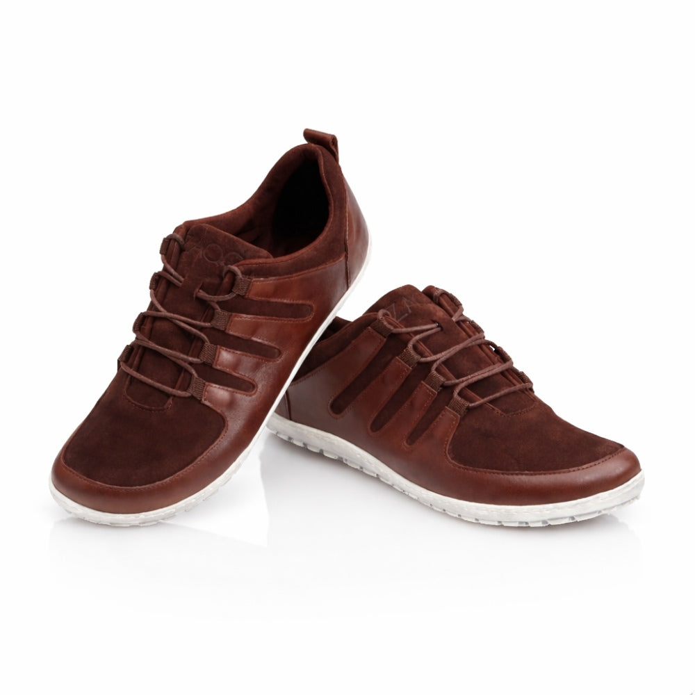 The SHOQQ Dark Brown sneakers from ZAQQ are made from leather with suede accents and a distinctive lace-up design, complemented by rubber soles that contrast sharply with the white background. These elements give the sneaker a casual yet stylish look and make it an ideal barefoot shoe for any occasion.