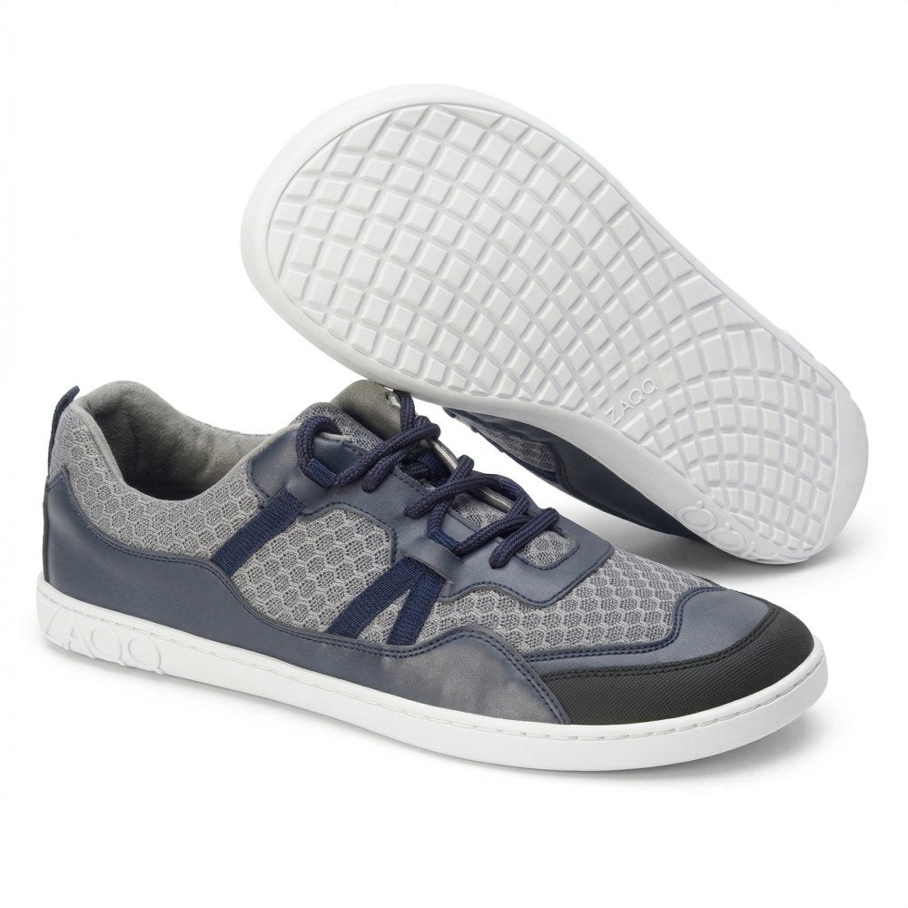 A pair of SQATE Gray sneakers from ZAQQ with chic gray and blue mesh accents and white soles. One shoe is positioned sideways to show off the grid pattern on the sole, while the other stands upright to highlight the laces and upper design.
