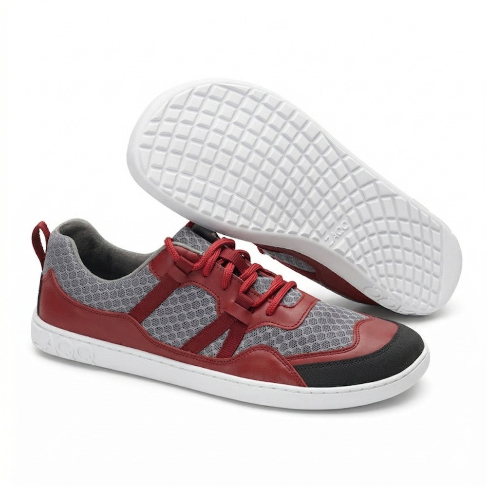 A pair of SQATE Red sports shoes from ZAQQ featuring red and gray mesh uppers, black accents and red laces. Designed for ultimate comfort, they feature a cream sole with a textured grid pattern and the brand's OO logo on the outsole.