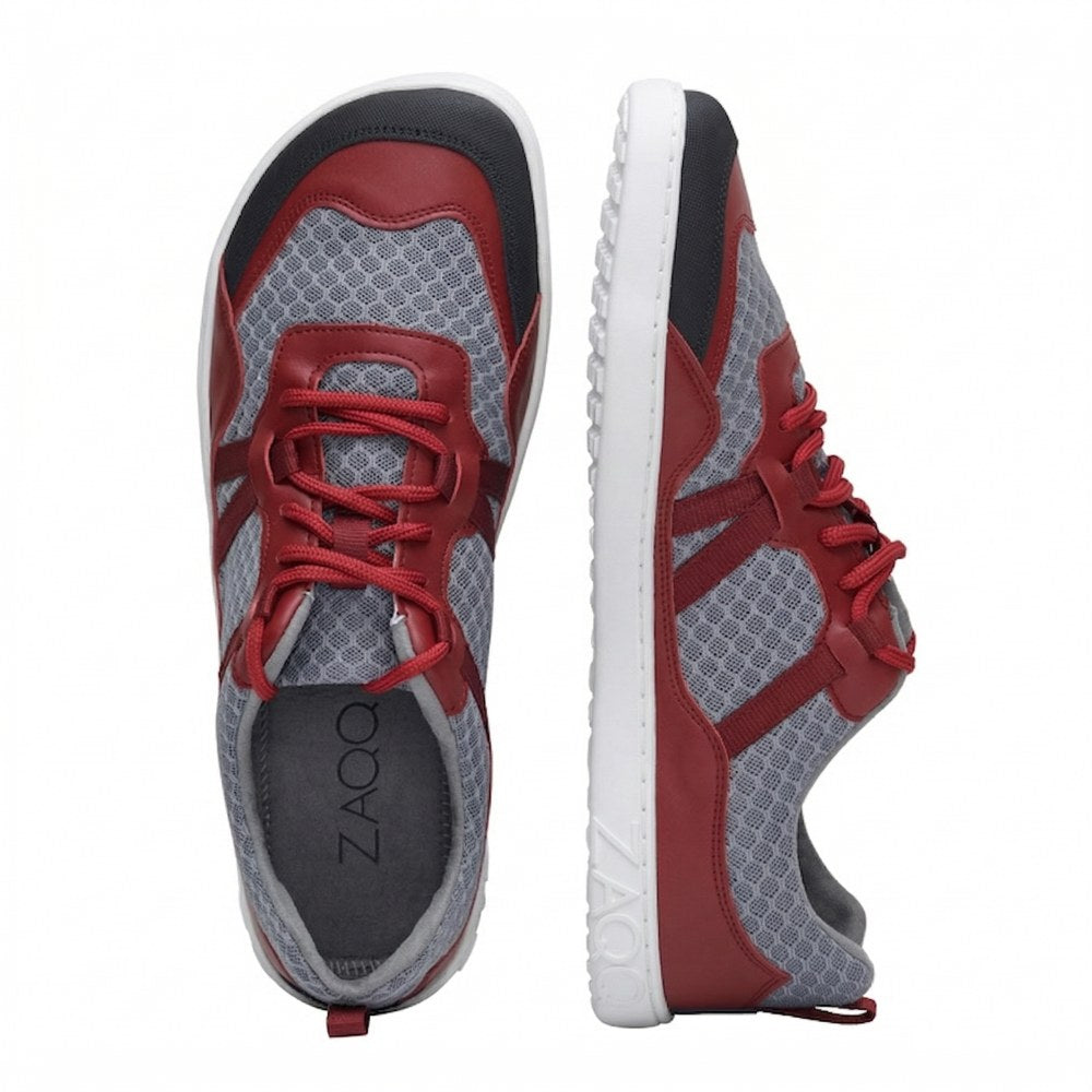 A pair of sports shoes from ZAQQ, one from above and the other from the side, with a red and gray design. They're made from mesh fabric, accented with red laces and have a white sole with the brand name embossed on them. Experience optimal comfort with every step with these stylish SQATE Red shoes.