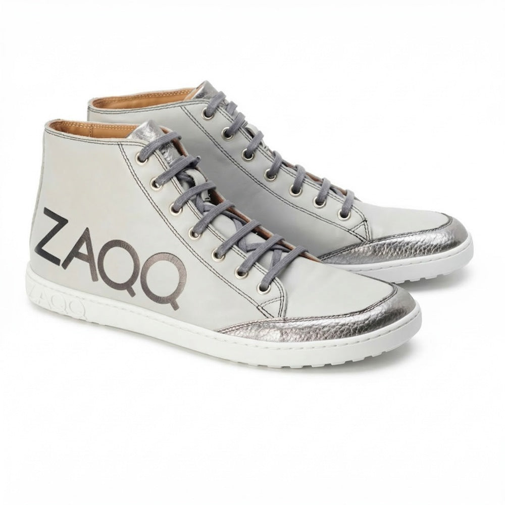 Discover the ideal combination of style and comfort with the SQYLA Gray high-top sneakers from ZAQQ. Adorned with silver metallic accents and branded details, these sneakers are crafted from premium nappa leather. They feature a classic lace-up design paired with a white rubber sole that provides a subtle distressed look.