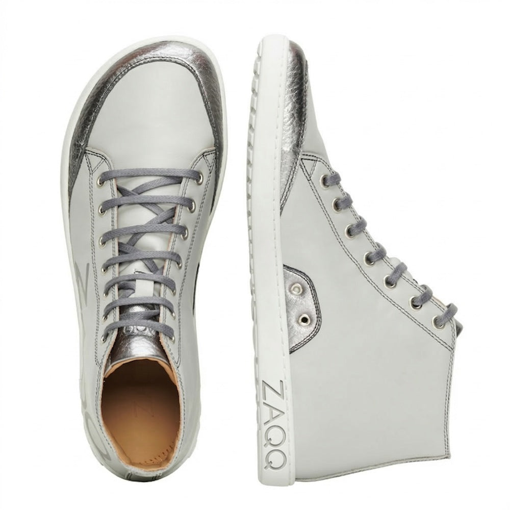 We present the SQYLA Gray from ZAQQ: a pair of stylish nappa leather high-top sneakers with eye-catching silver and gray accents. The design features one shoe from the top and another from the side, highlighting their elegant appearance, distinctive branding on the sole and a durable rubber sole for enhanced comfort.