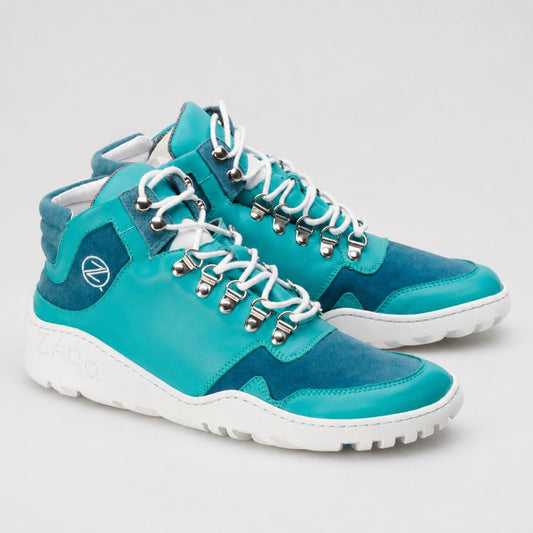 Ein Paar wasserdichte VAQATION Blue High-Top-Sneaker von ZAQQ mit weißen Schnürsenkeln und einer TERRA-Sohle. Diese stylischen Schuhe haben silberne Ösen und ein kleines rundes Logo an der Seite und kombinieren glatte und Wildlederoberflächen für zusätzlichen Stil und Komfort.
