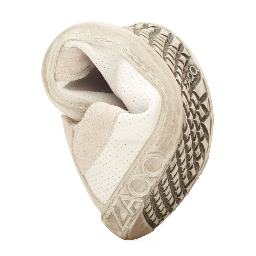 Der QORE Low White von ZAQQ zeichnet sich durch ein weiches, flexibles Design aus Nappaleder aus, das sich in eine kompakte Form drehen lässt und so seine Biegsamkeit demonstriert. Seine Sohle weist ein strukturiertes Muster auf, auf dem der Markenname ZAQQ deutlich zu sehen ist. Dieser Schuh ist überwiegend weiß mit dezenten beigen Akzenten.